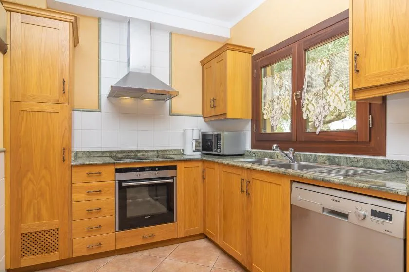 A fitted kitchen with wooden cabinets, a tiled backsplash, and a window above the counter.