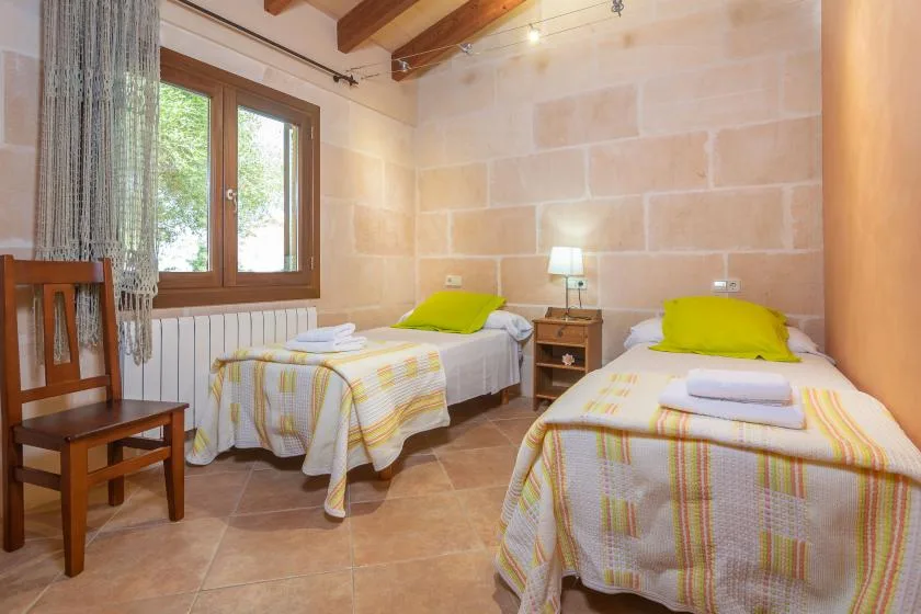 A twin bedroom with two single beds, colorful bedding, and a window.