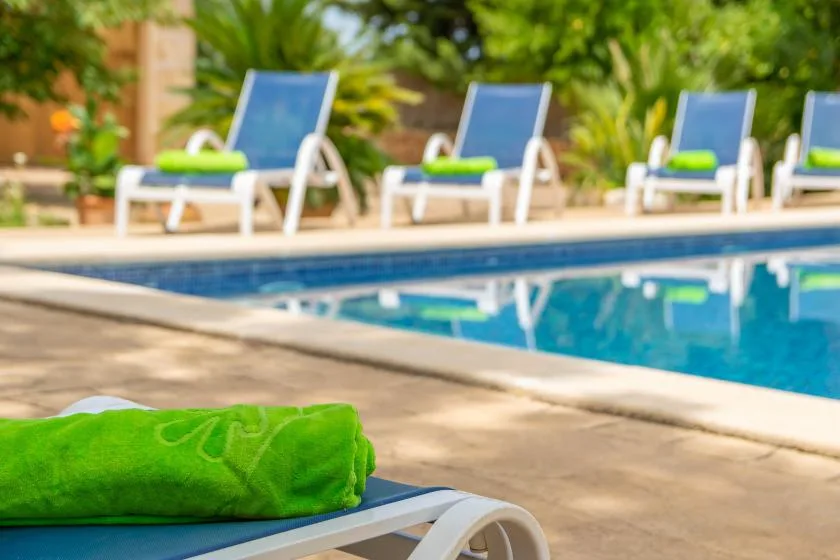 A swimming pool with lounge seating and a bright green towel in the foreground.