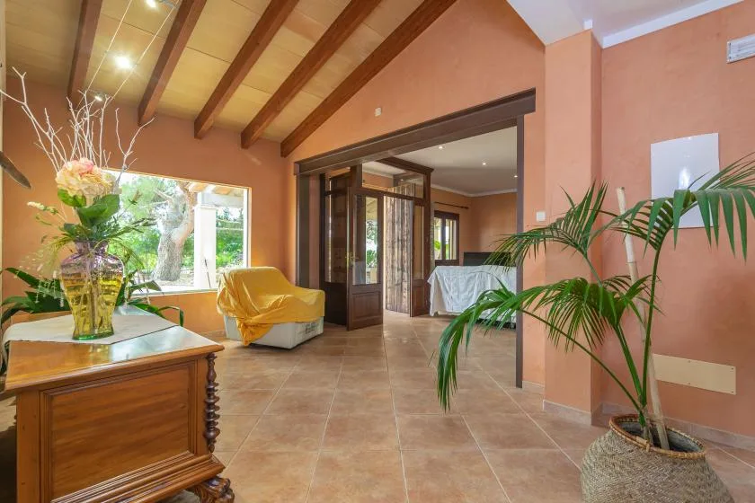 A warm-toned interior with an open doorway, tiled floor, and potted plants.