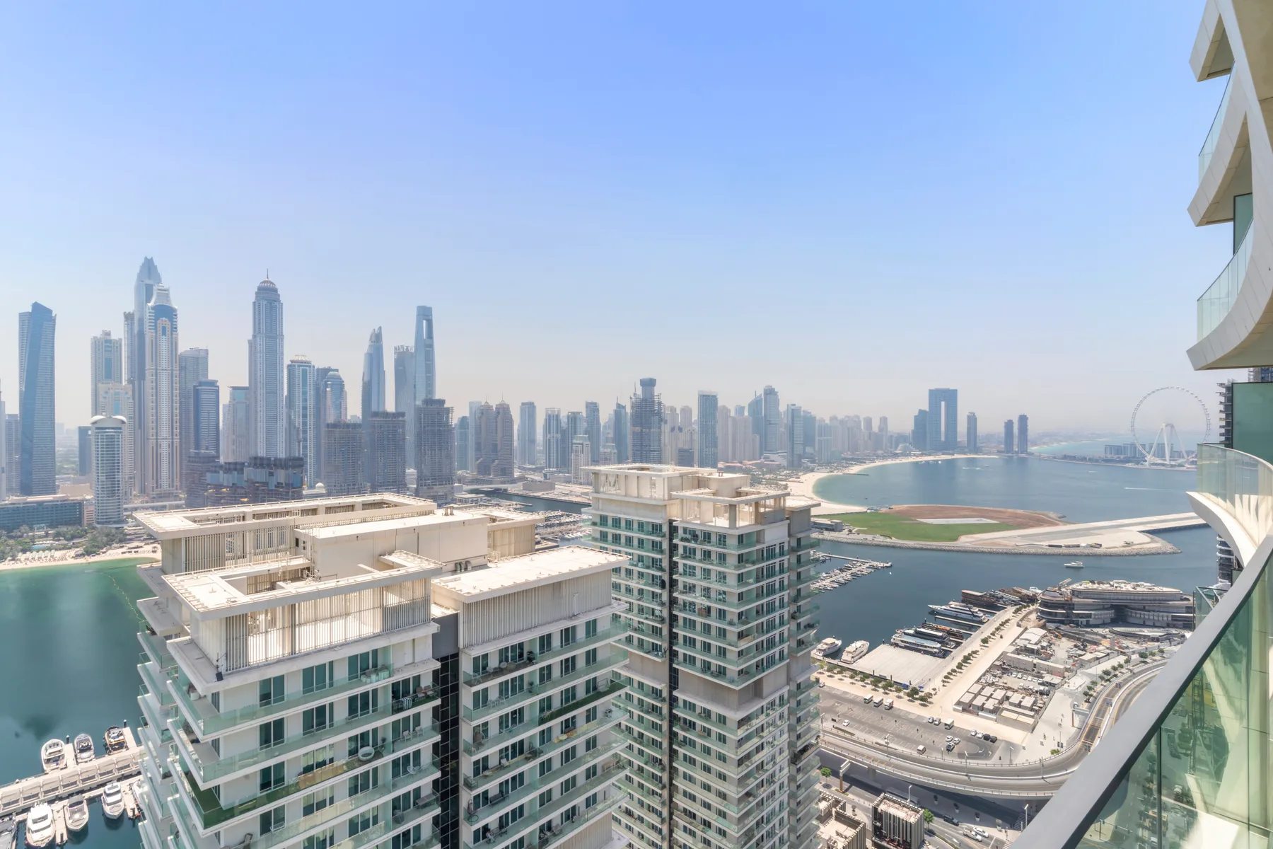 A balcony overlooks the Dubai skyline and a curved stretch of coastline.