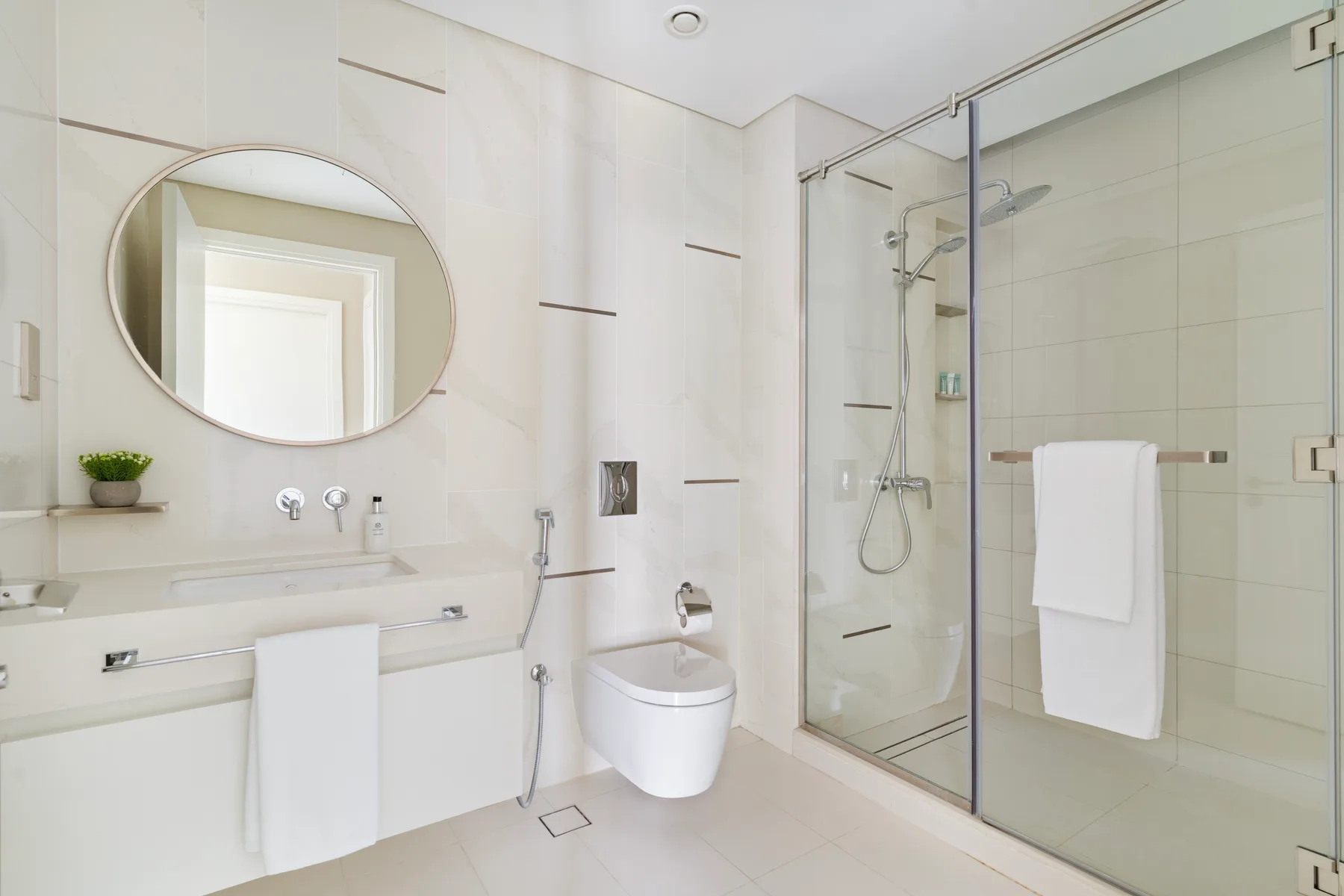 A bright bathroom with a glass-enclosed shower and wall-mounted sink.