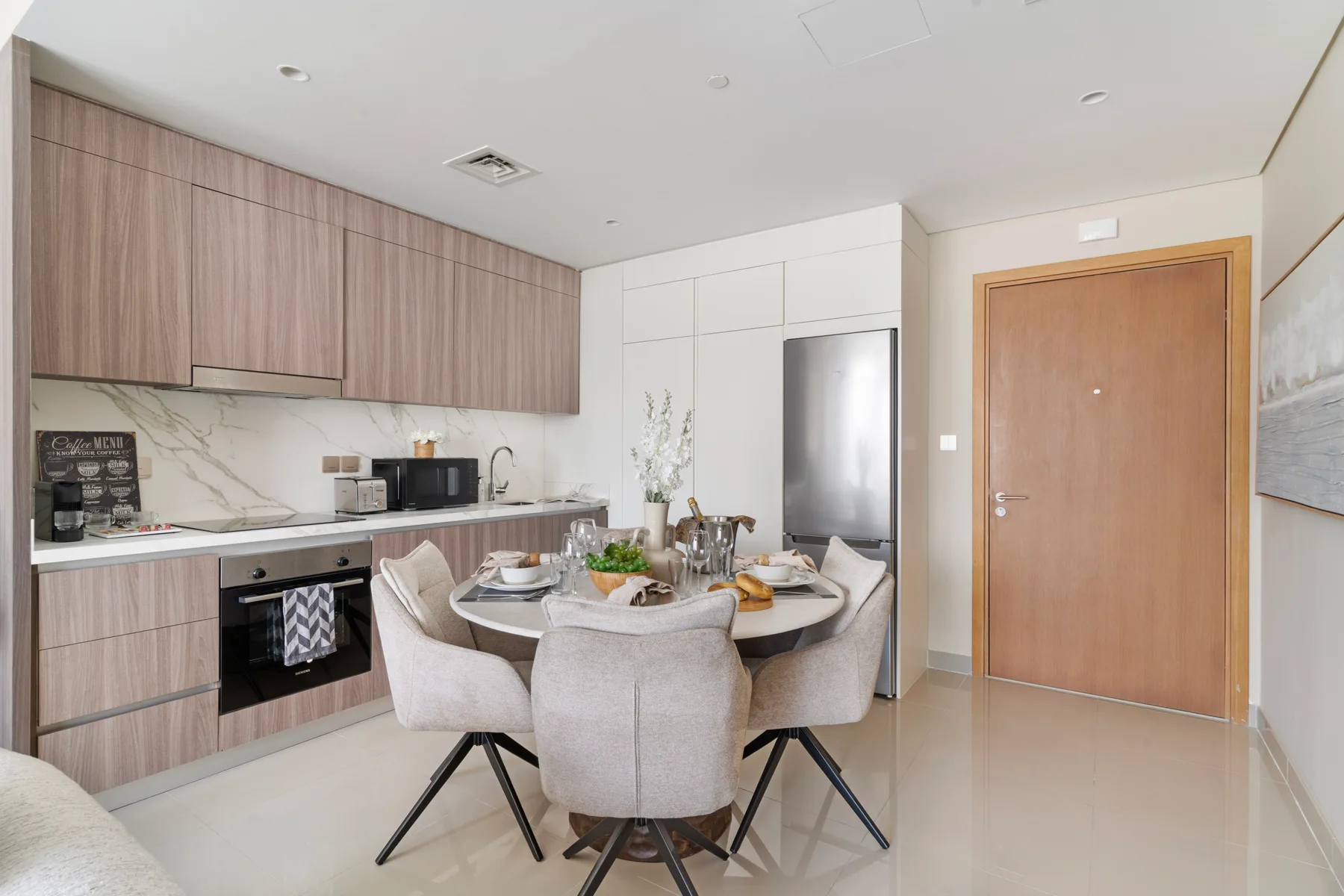 A dining area with upholstered seating beside a modern kitchen.