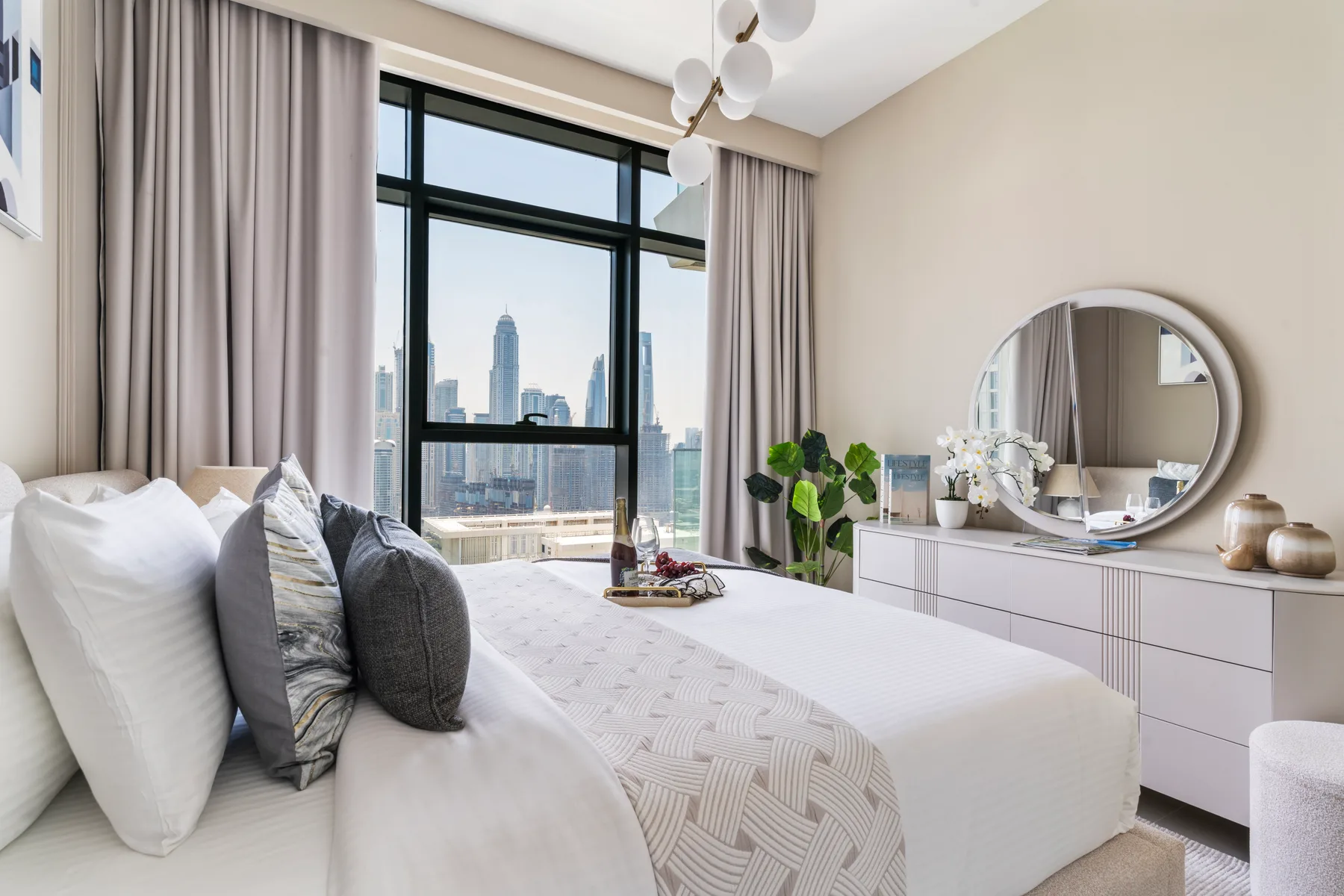 A bright bedroom with a large bed beside a floor-to-ceiling window.
