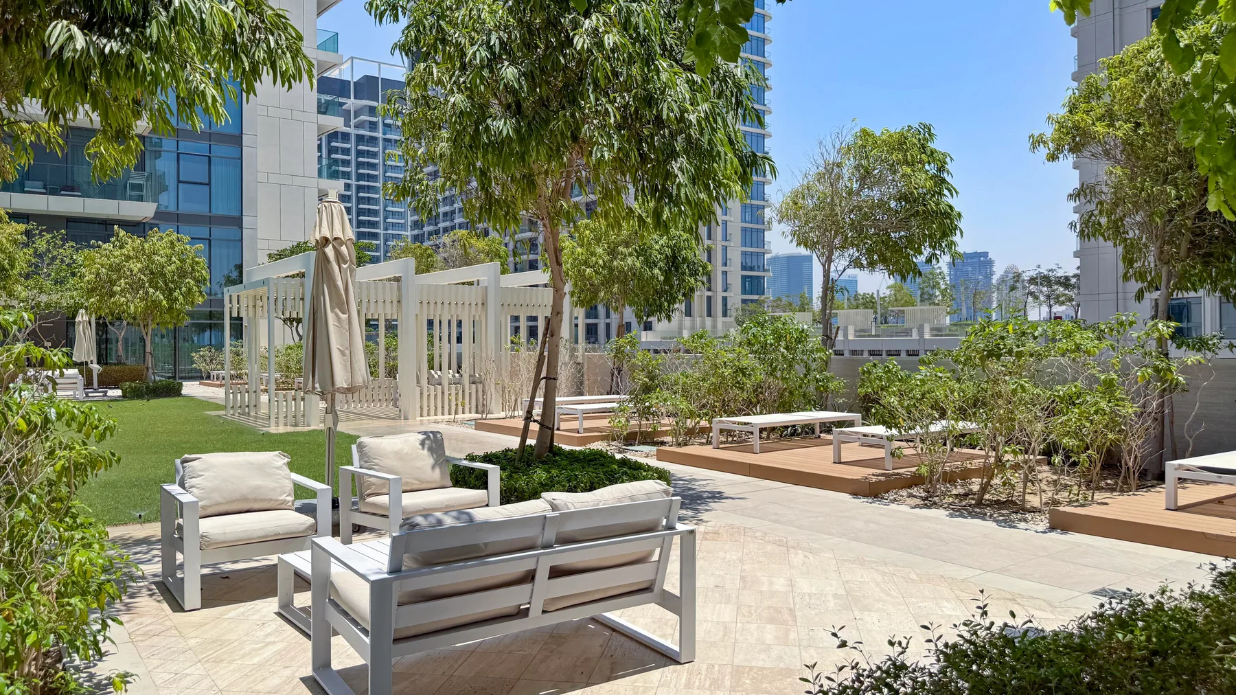 An outdoor terrace with lounge seating, trees, and landscaped planters.
