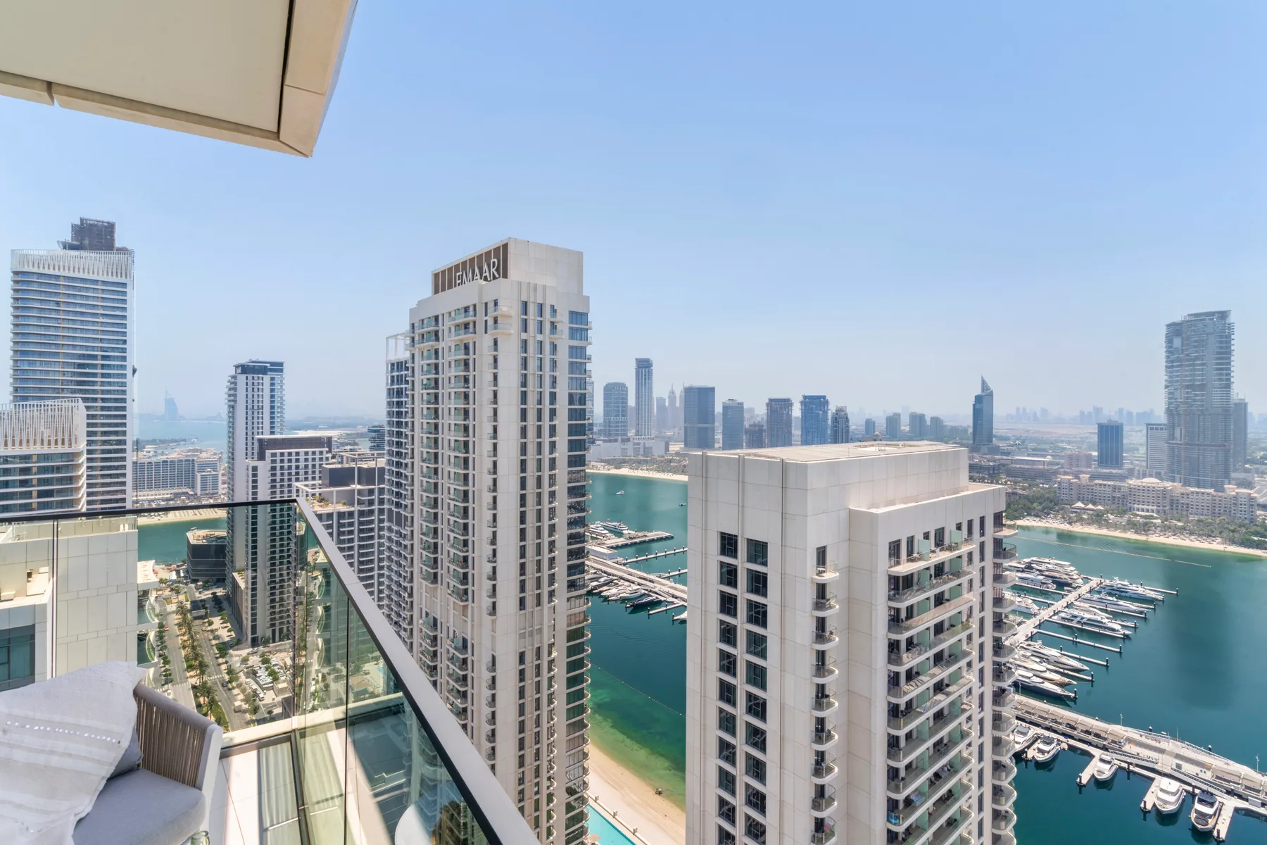 A high-rise balcony overlooks the marina and surrounding city skyline.