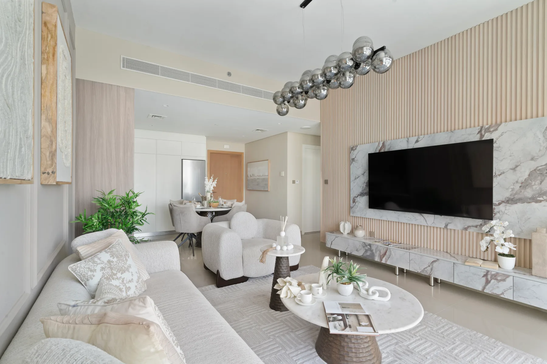 A bright living room with seating, a coffee table, and a wall-mounted television.