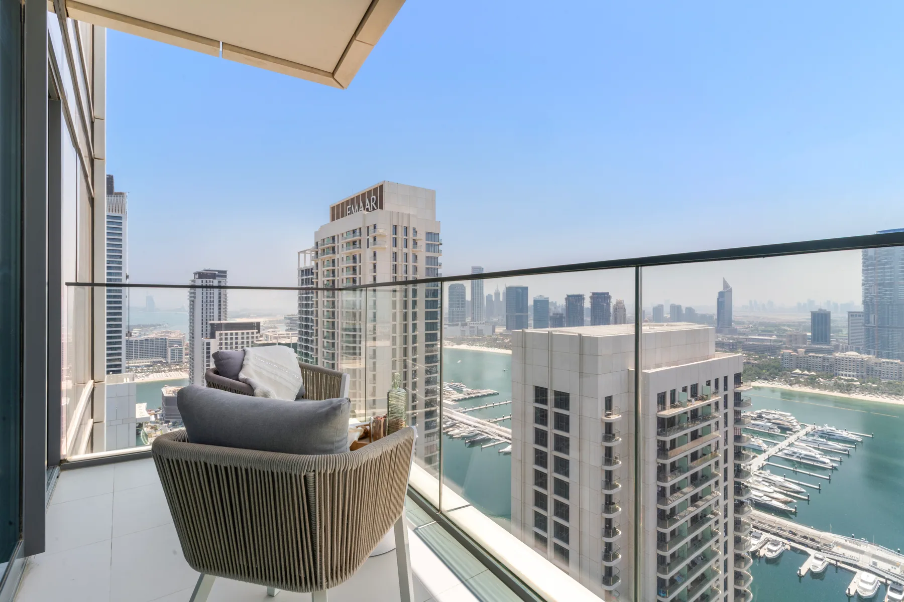 A balcony seating area overlooks high-rise buildings and a marina.