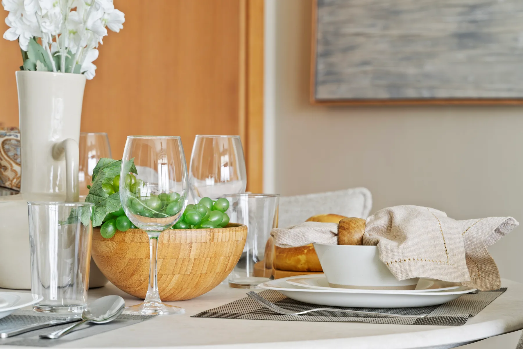 A dining table is set with glassware, a bowl of green olives, and bread.
