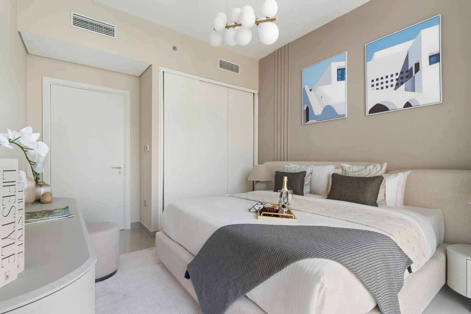 A bedroom with a neatly made bed, gray throw, and abstract artwork on the wall.
