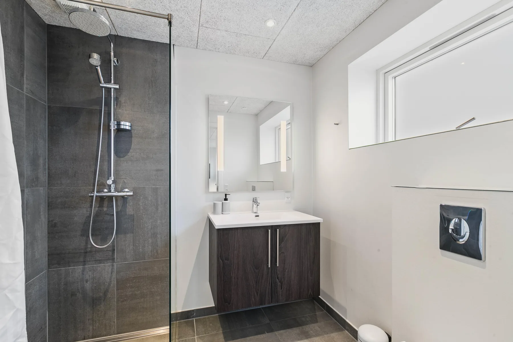 Un baño moderno con ducha de cristal y lavabo con mueble.
