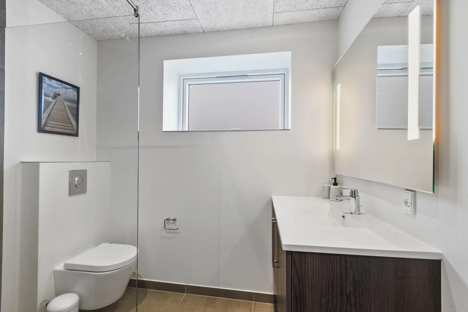 Un baño con un inodoro y un lavabo bajo un espejo de pared.