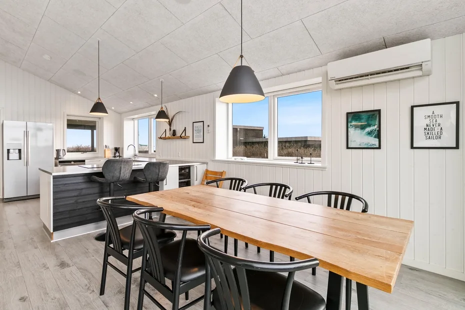 Una luminosa cocina con comedor cuenta con una mesa larga de madera e isla.