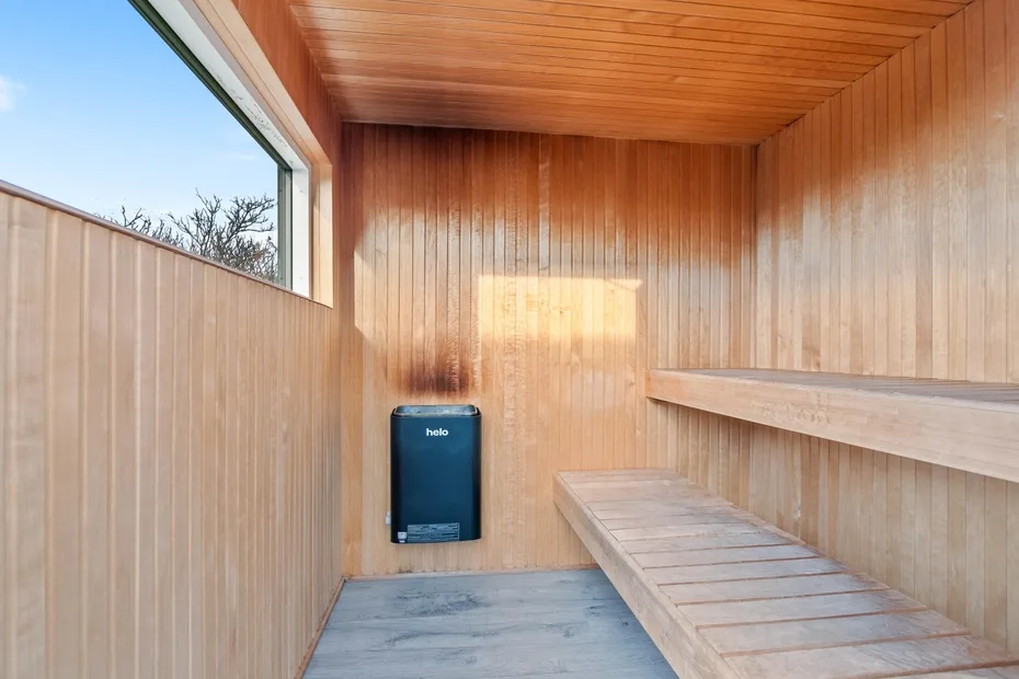 Una sauna revestida de madera con un banco largo y una ventana.