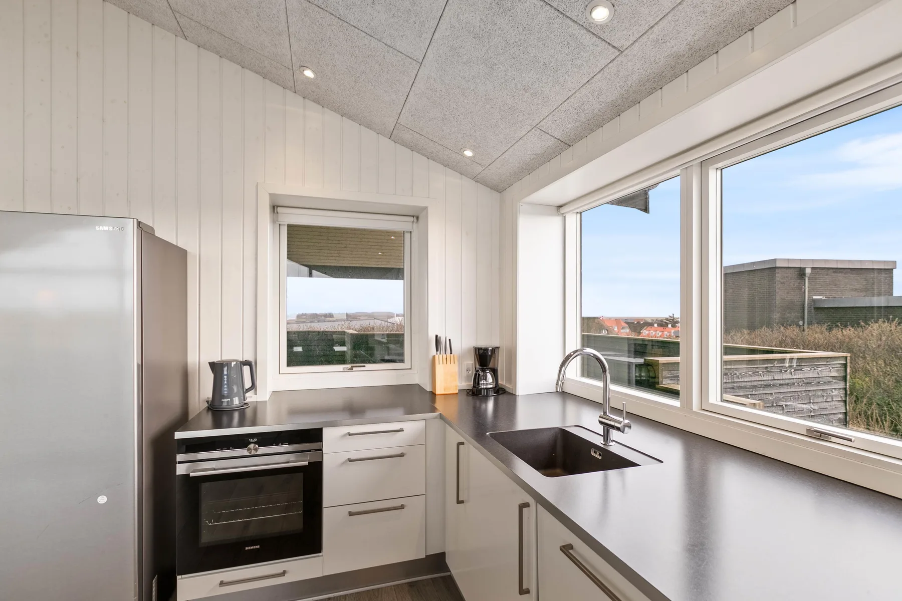 Una cocina luminosa con horno integrado y ventanas grandes.