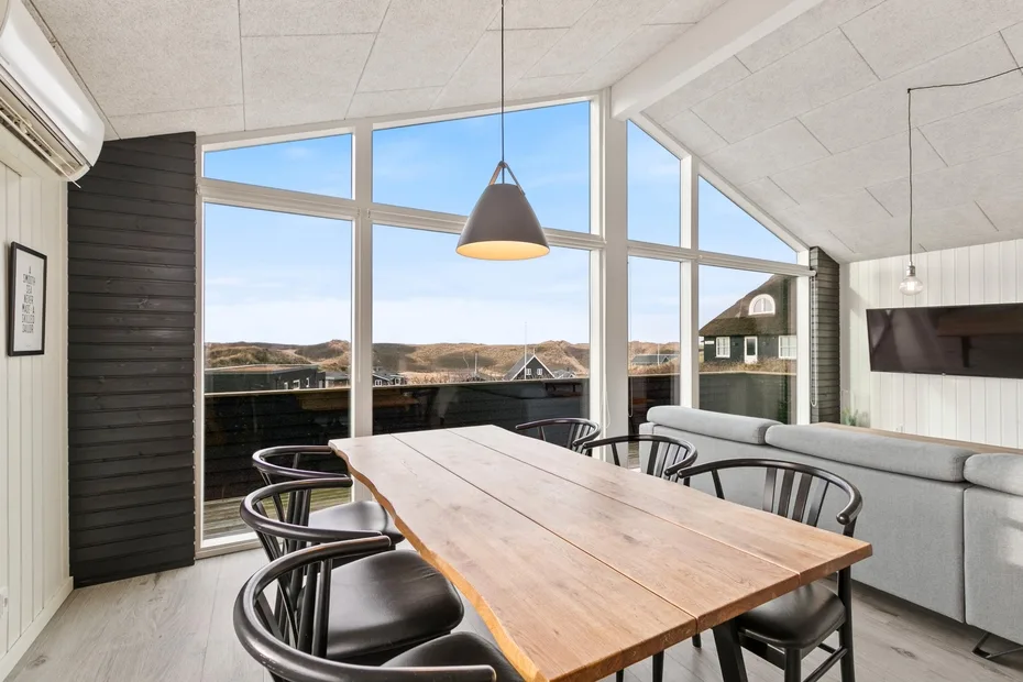 Comedor con una mesa larga de madera y grandes ventanas con vistas al paisaje.