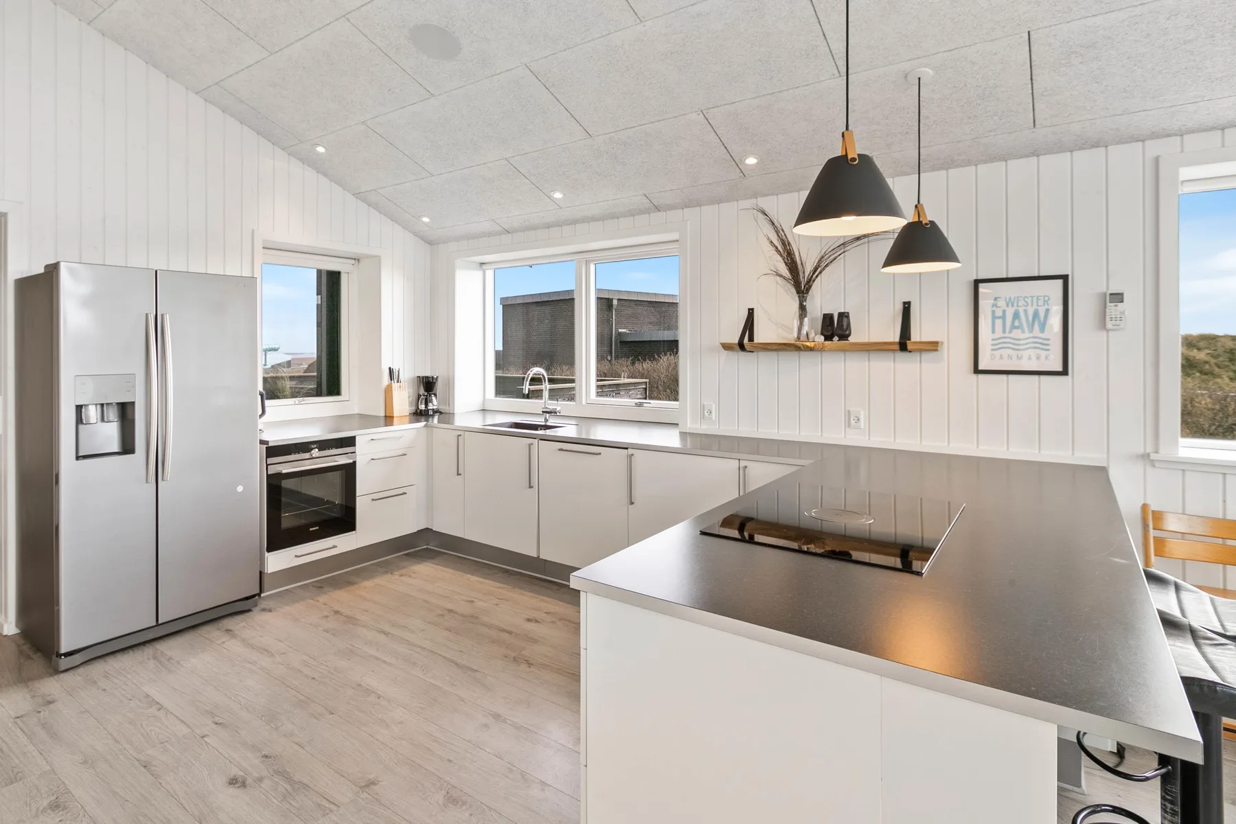 Una cocina luminosa con gabinetes blancos, una isla central y ventanas.
