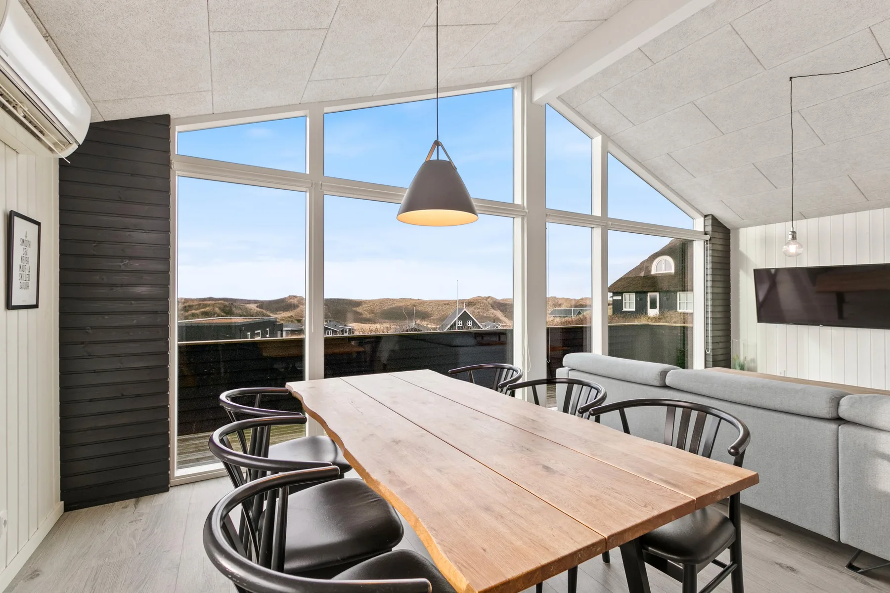 Comedor con una mesa de madera y grandes ventanales con vistas al paisaje.