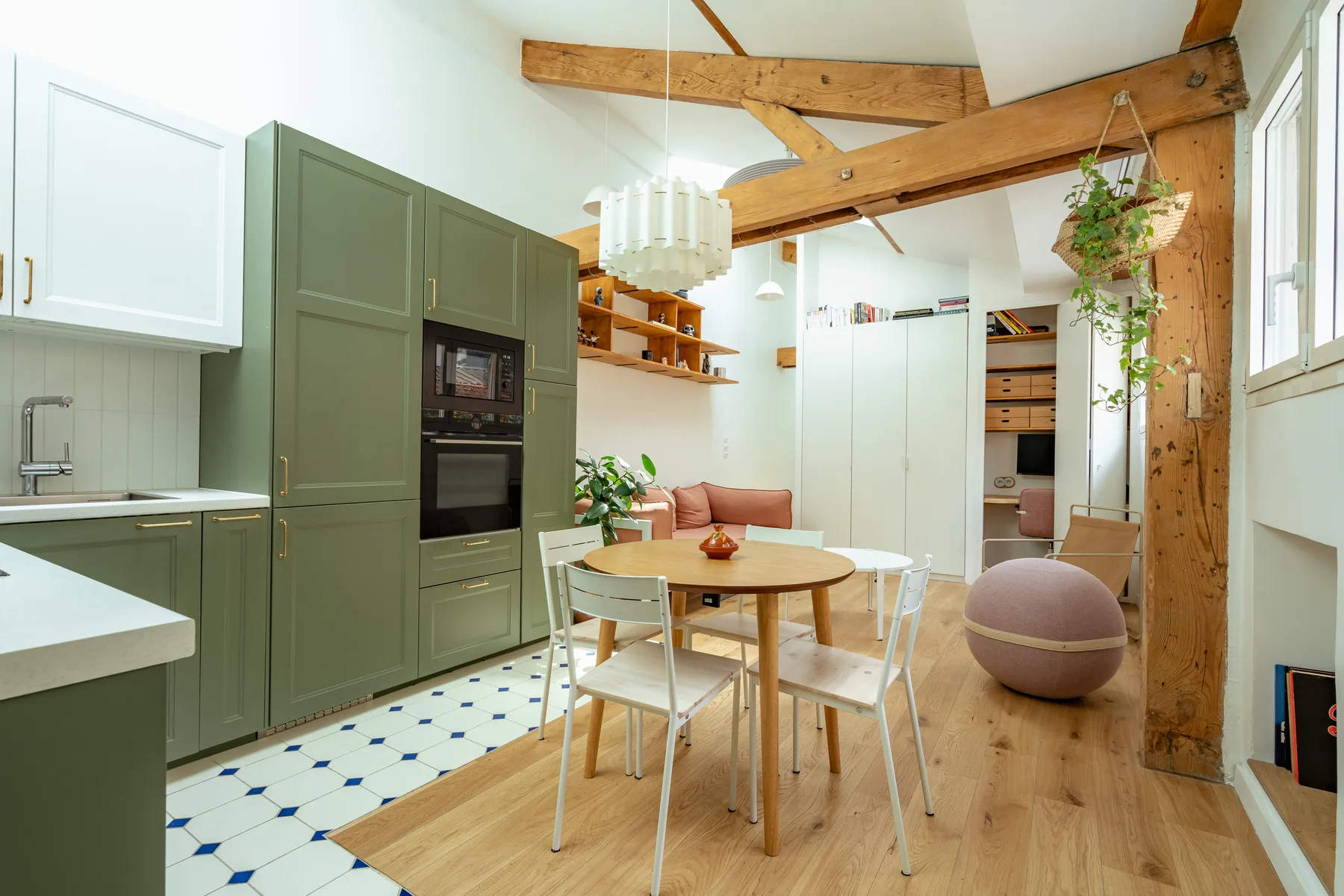 Una cocina abierta al comedor, con una mesa redonda y vigas de madera a la vista.