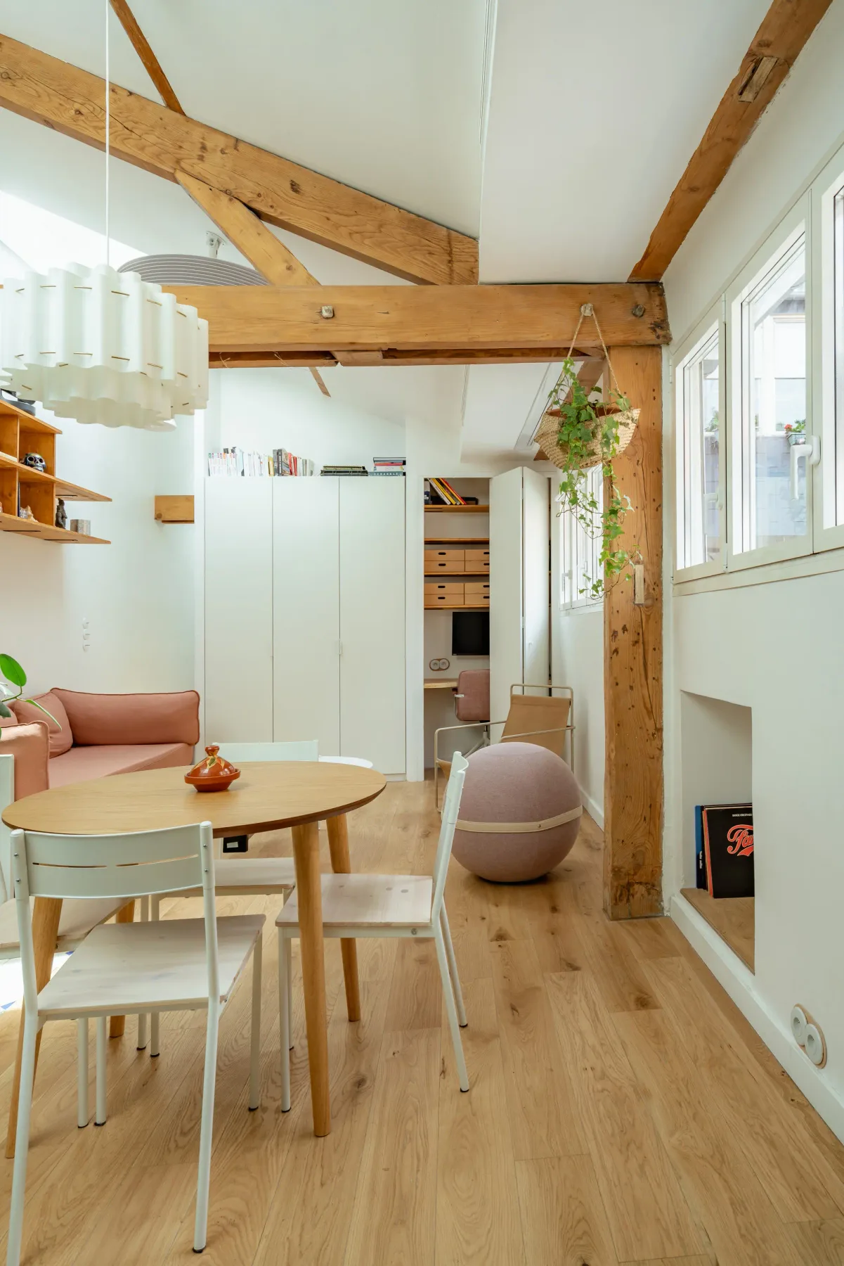 Un comedor luminoso con una mesa de madera y asientos bajo vigas expuestas.
