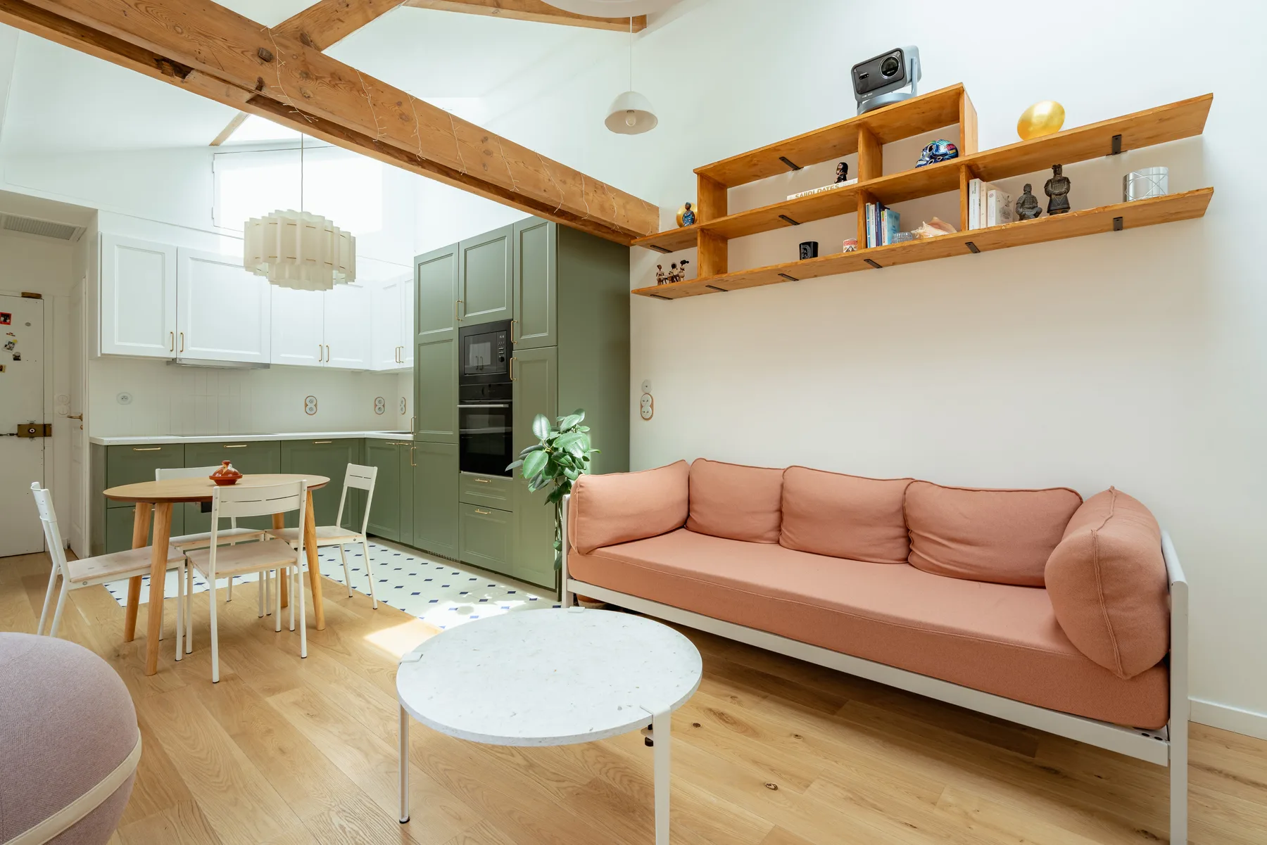 Una luminosa sala de estar y comedor con un sofá color salmón y estantes de madera.