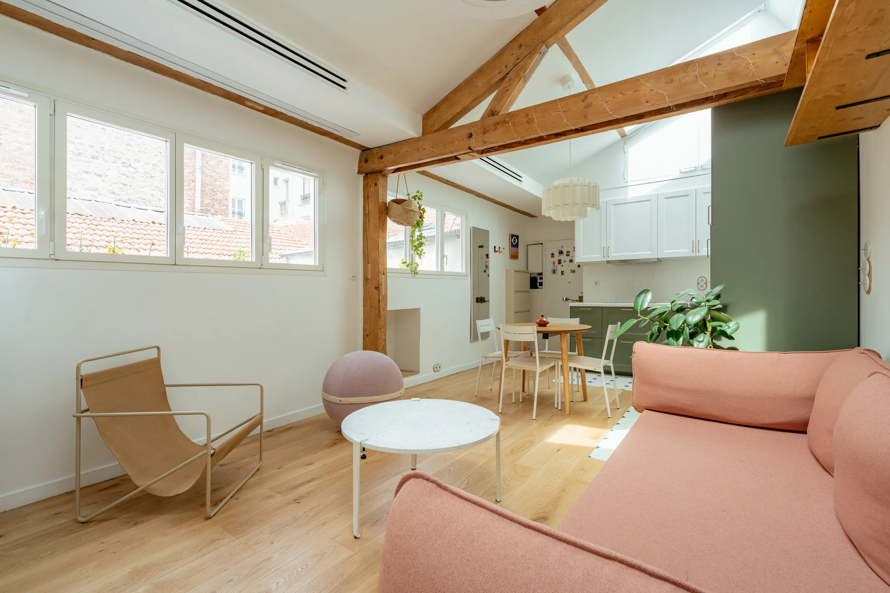 Una luminosa sala de estar y comedor de espacio abierto, con grandes ventanas y vigas de madera a la vista.
