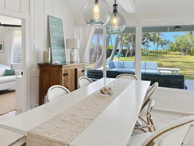 Un comedor luminoso se abre a un patio con palmeras y vistas al mar.