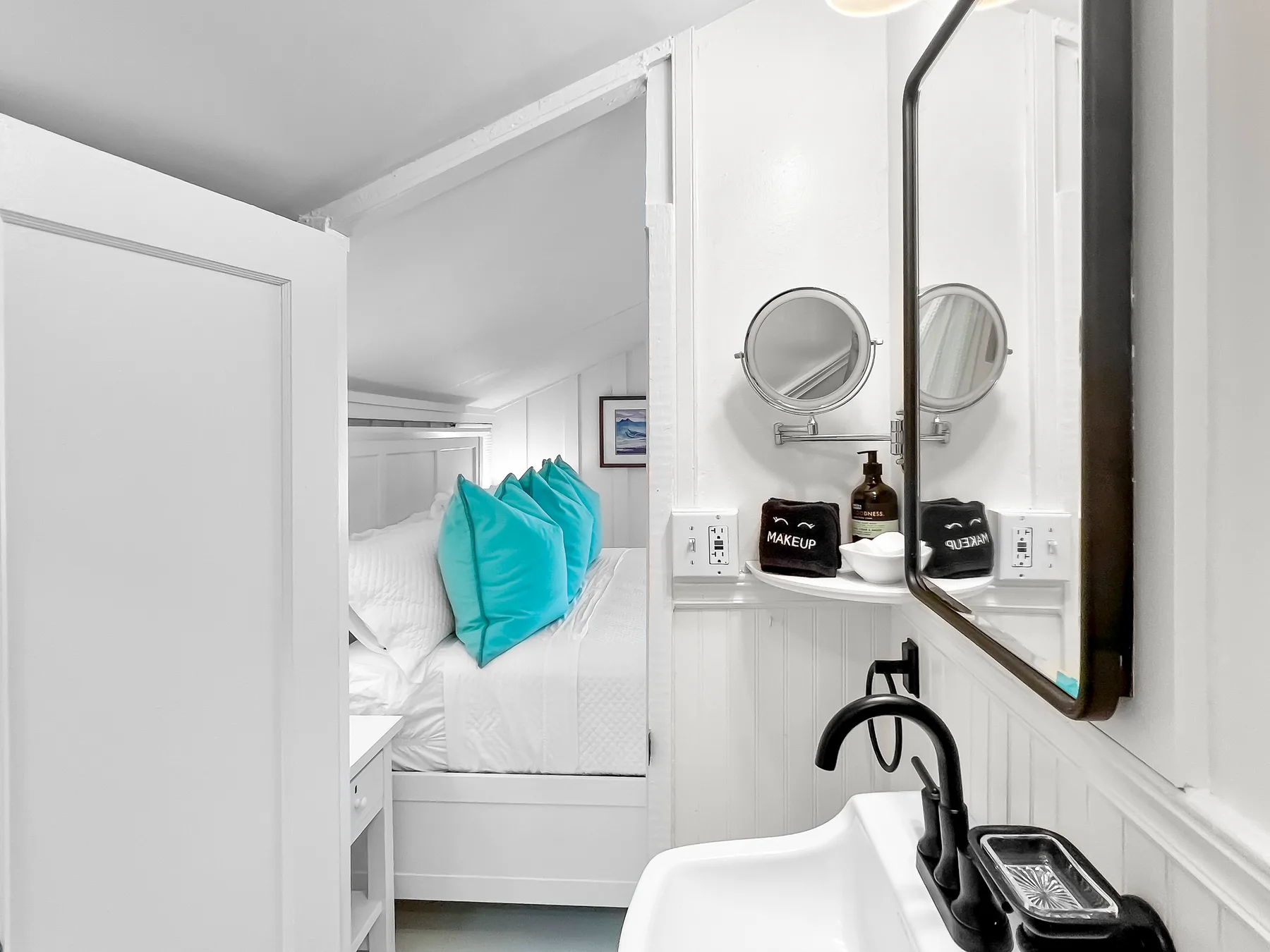 Un dormitorio luminoso con almohadas turquesas junto a un lavabo compacto.