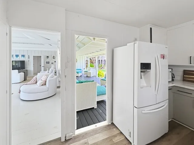 Una cocina luminosa y abierta da a una sala de estar y un porche soleado cerrado.