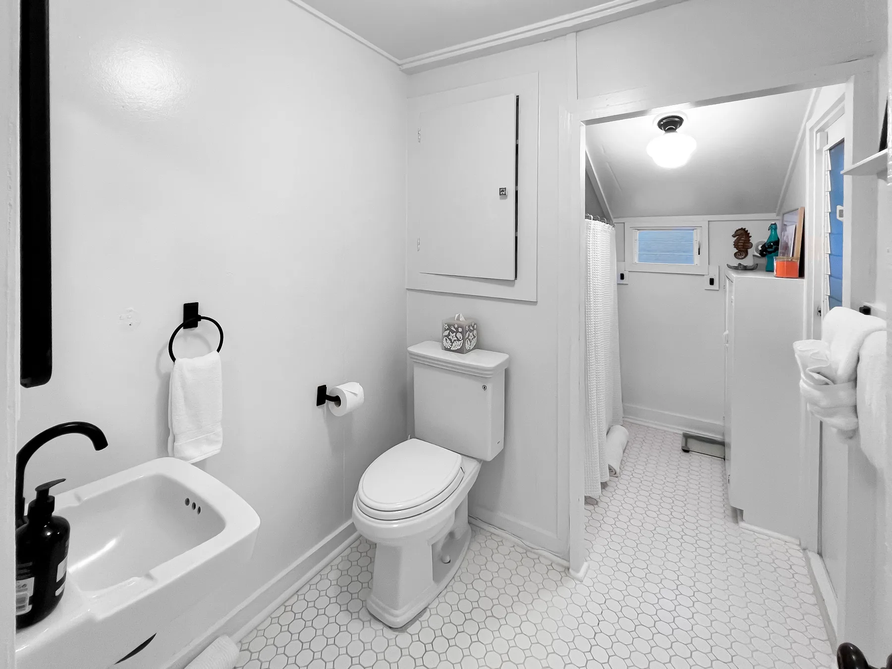 Un baño luminoso con inodoro, lavabo y suelo estampado.