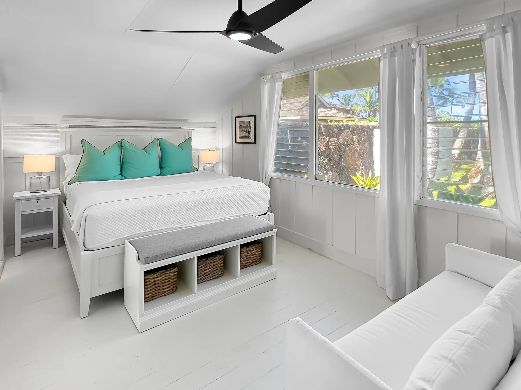 Un dormitorio luminoso con una cama bien hecha y ventanas grandes.