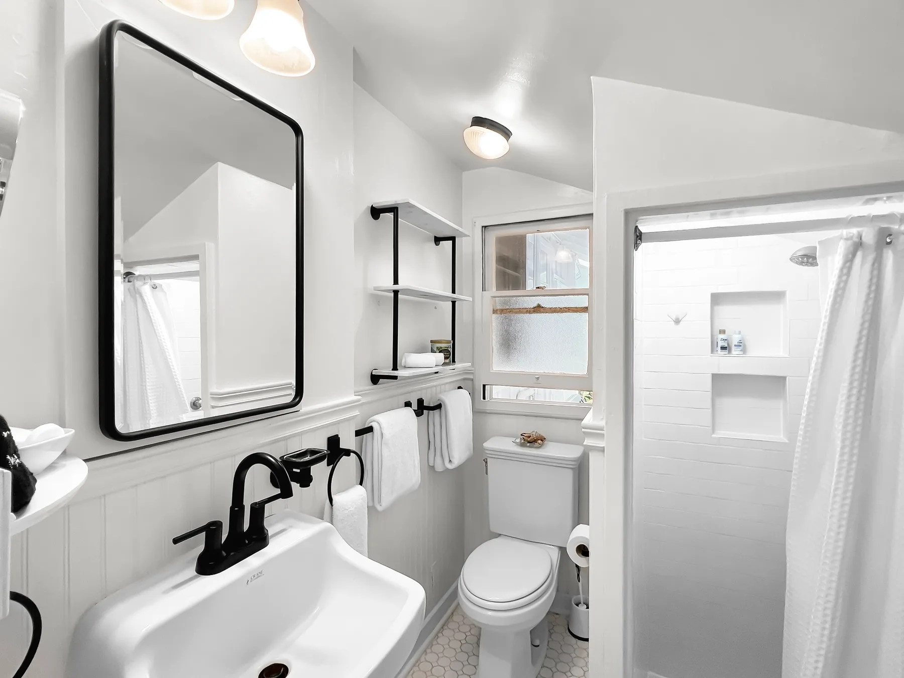 Un baño luminoso con lavabo, inodoro y ducha.
