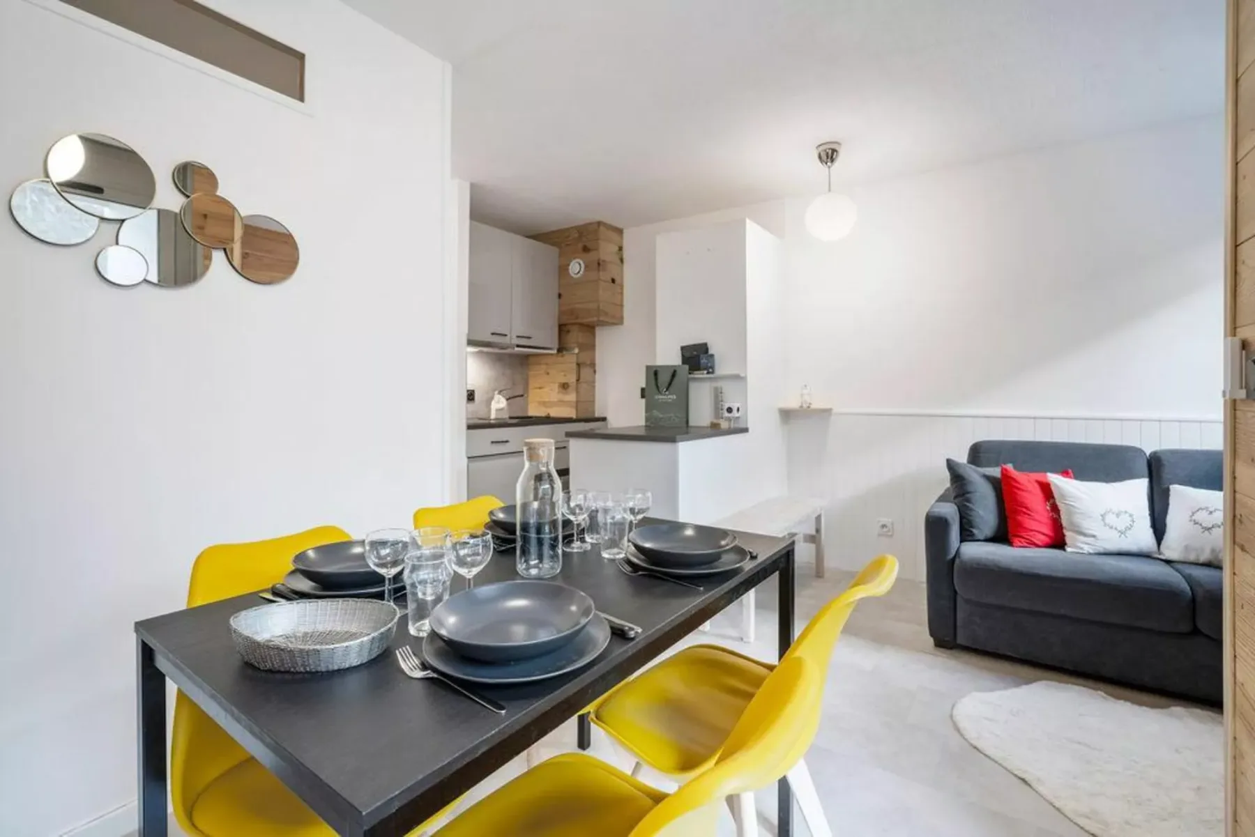 Sala de estar y comedor diáfanos con una mesa puesta y asientos.