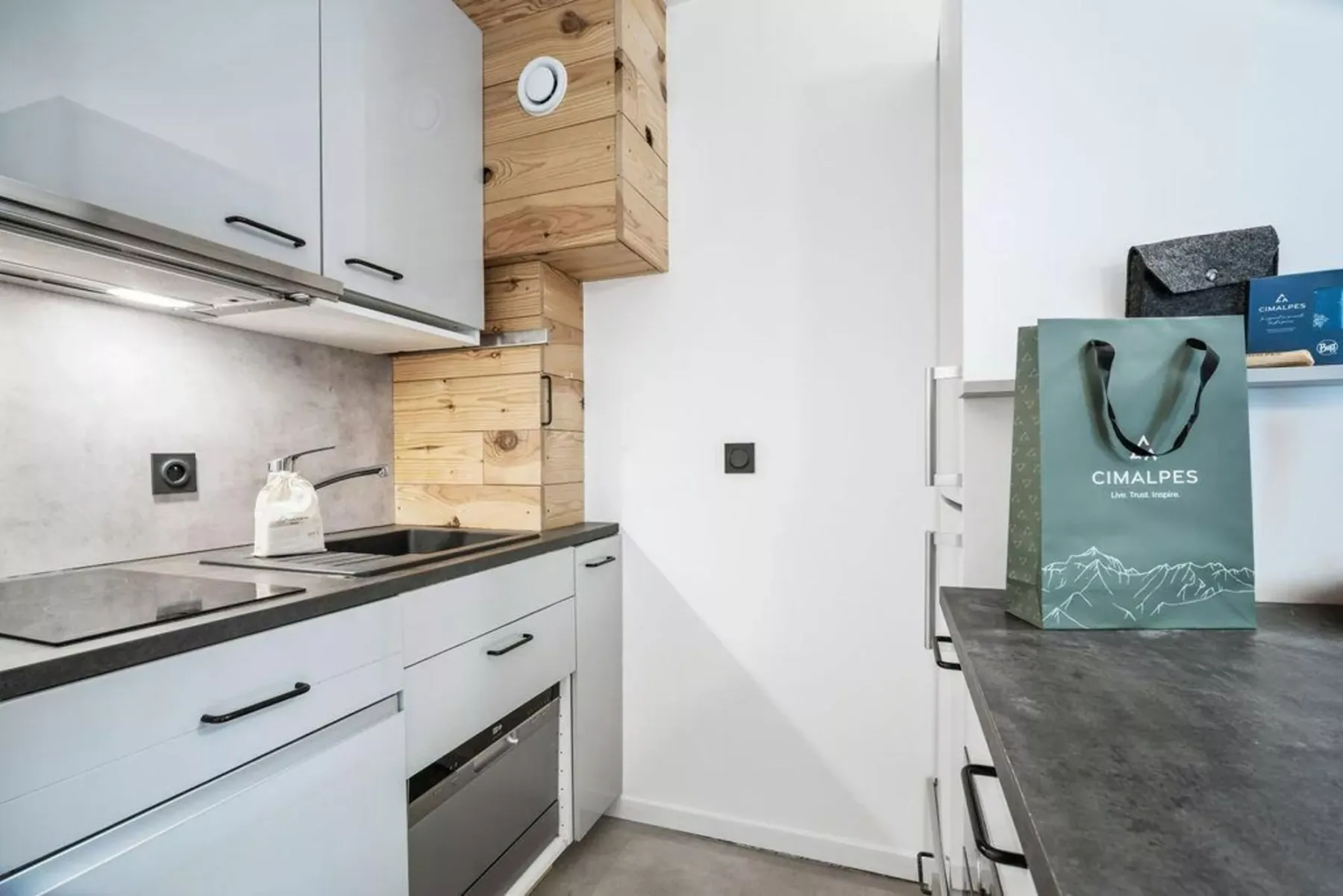 Una cocina compacta con armarios blancos, una placa de cocción y detalles de madera.