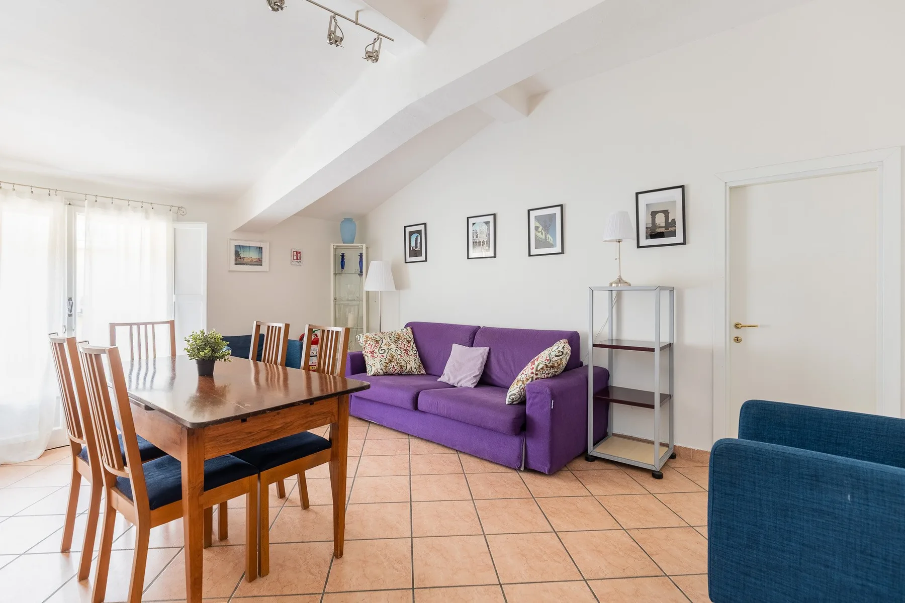 Una sala de estar y comedor con un sofá morado y una mesa de comedor de madera.