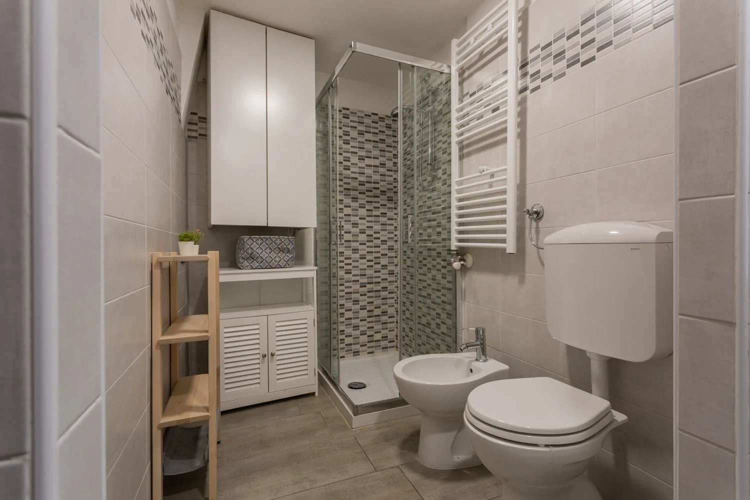 A tiled bathroom with a glass shower, sink, and toilet.