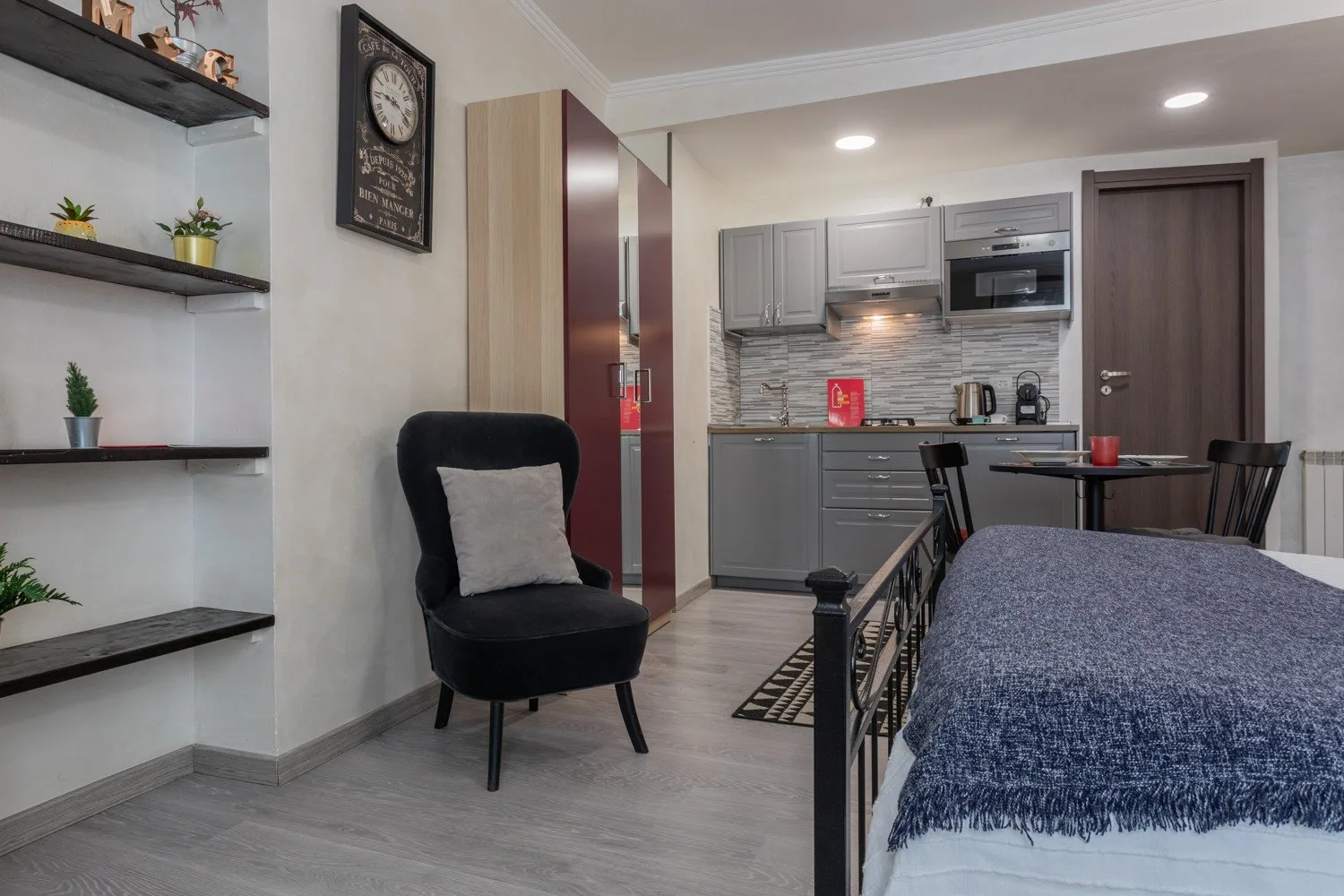 A compact kitchen and dining area with gray cabinets and a black armchair.