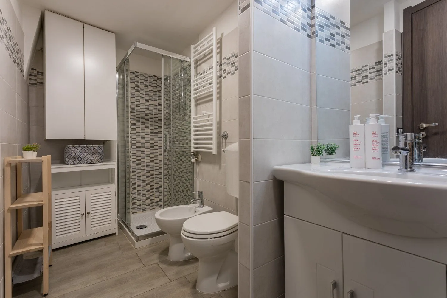 A tiled bathroom with a shower, toilet, and vanity.