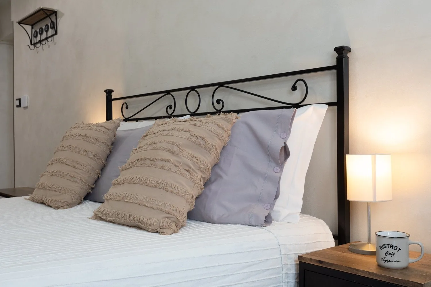 A bedroom with a neatly made bed and a bedside lamp.