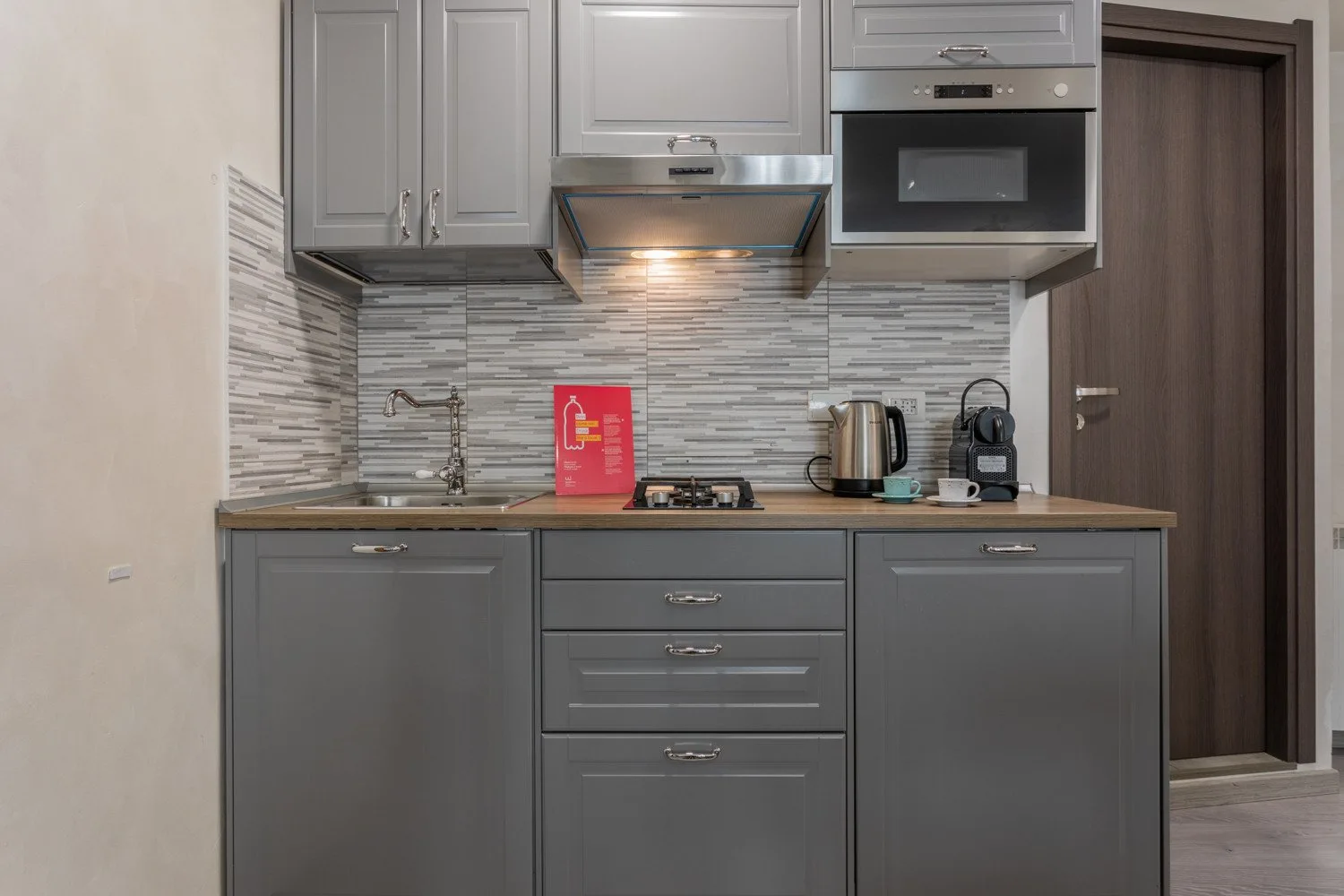 A modern kitchen with gray cabinets, a cooktop, and countertop appliances.