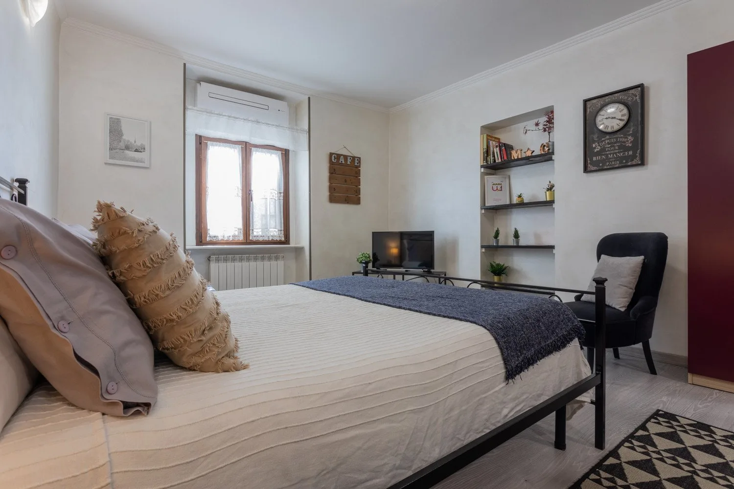 A bedroom with a bed, a window, and a small television.