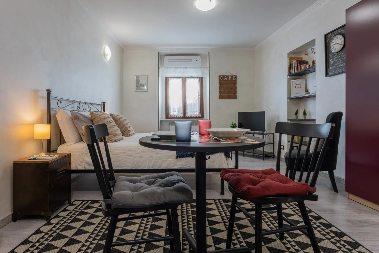 A bedroom and sitting area with a bed, dining table, and chairs.
