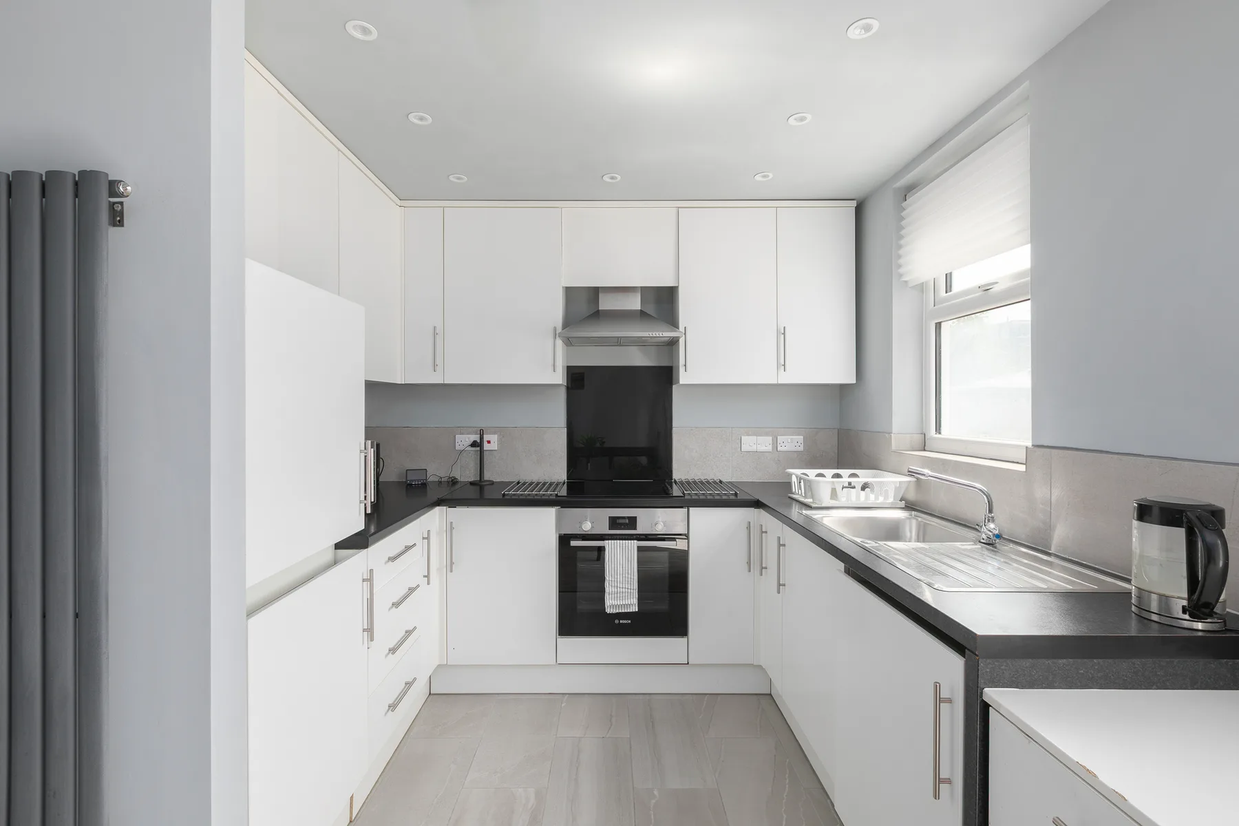 Una cocina luminosa con armarios blancos y una encimera junto a la ventana.
