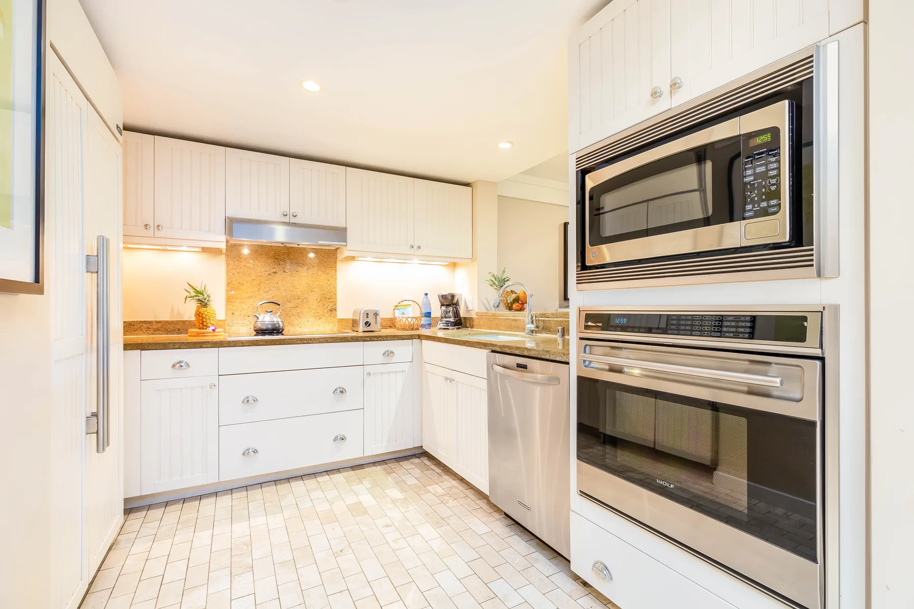 Una cocina luminosa con gabinetes blancos, encimeras y electrodomésticos integrados.