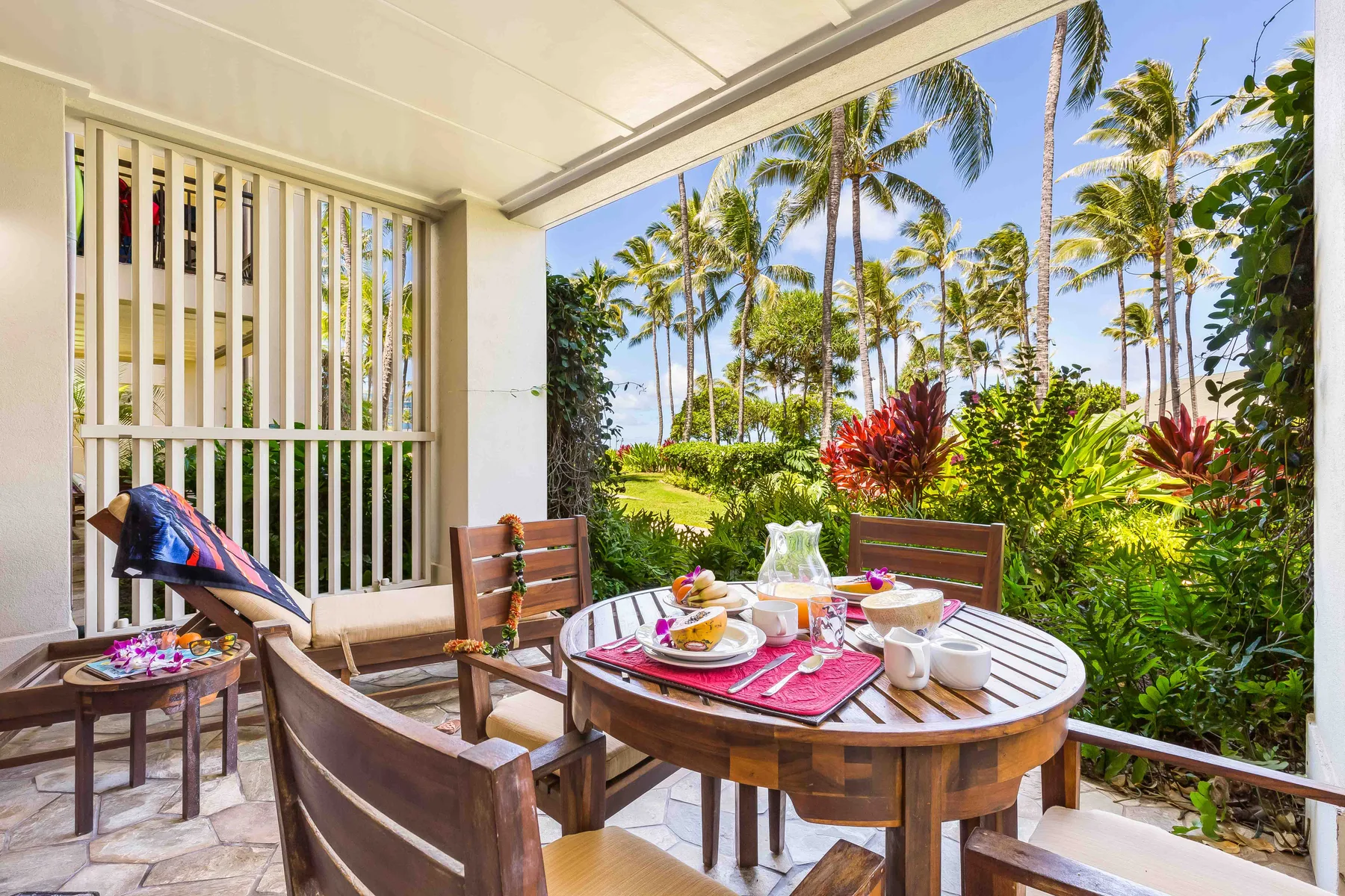 Un patio comedor al aire libre con una mesa redonda junto a un jardín tropical.