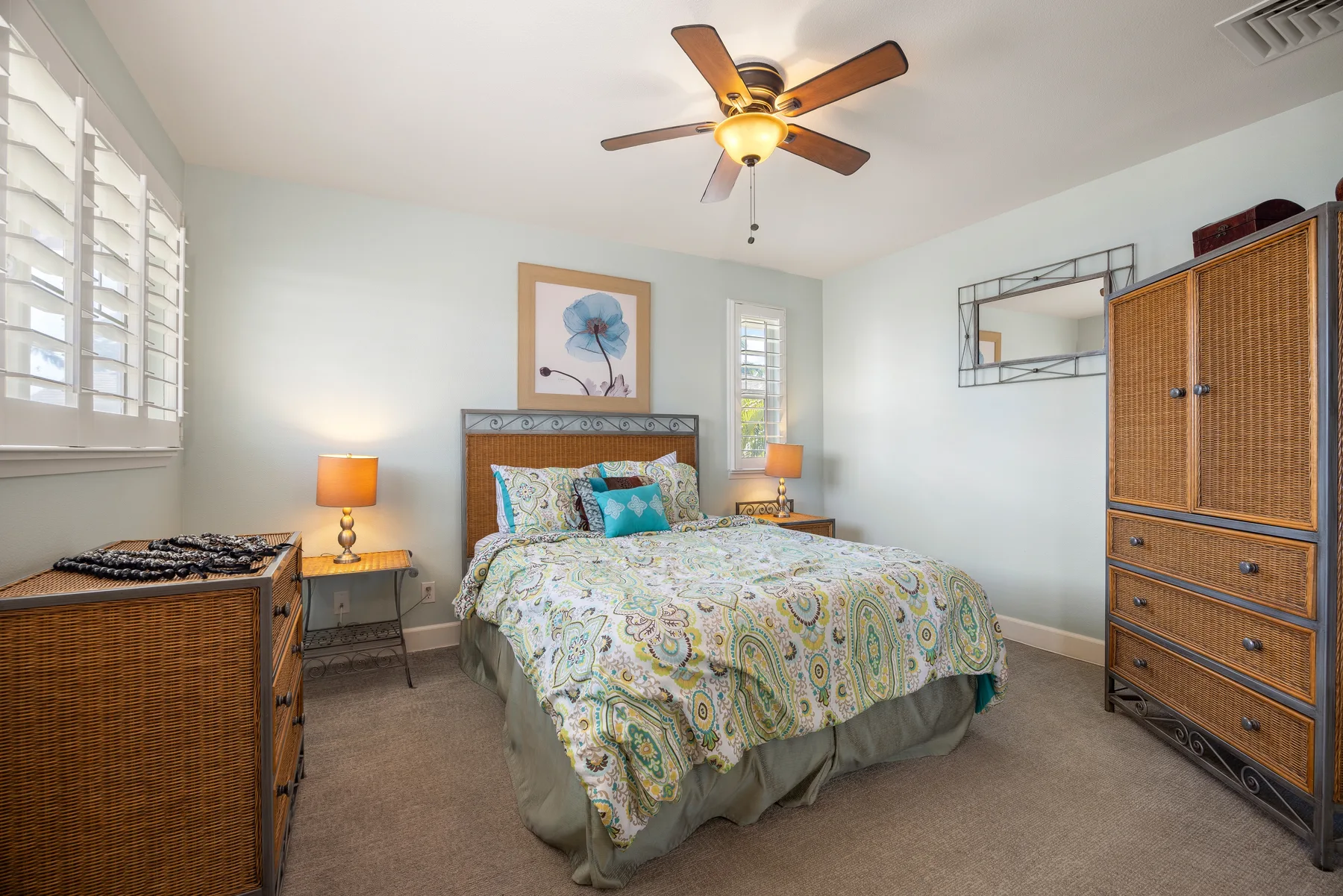 A bedroom with a bed, bedside tables, and a ceiling fan.