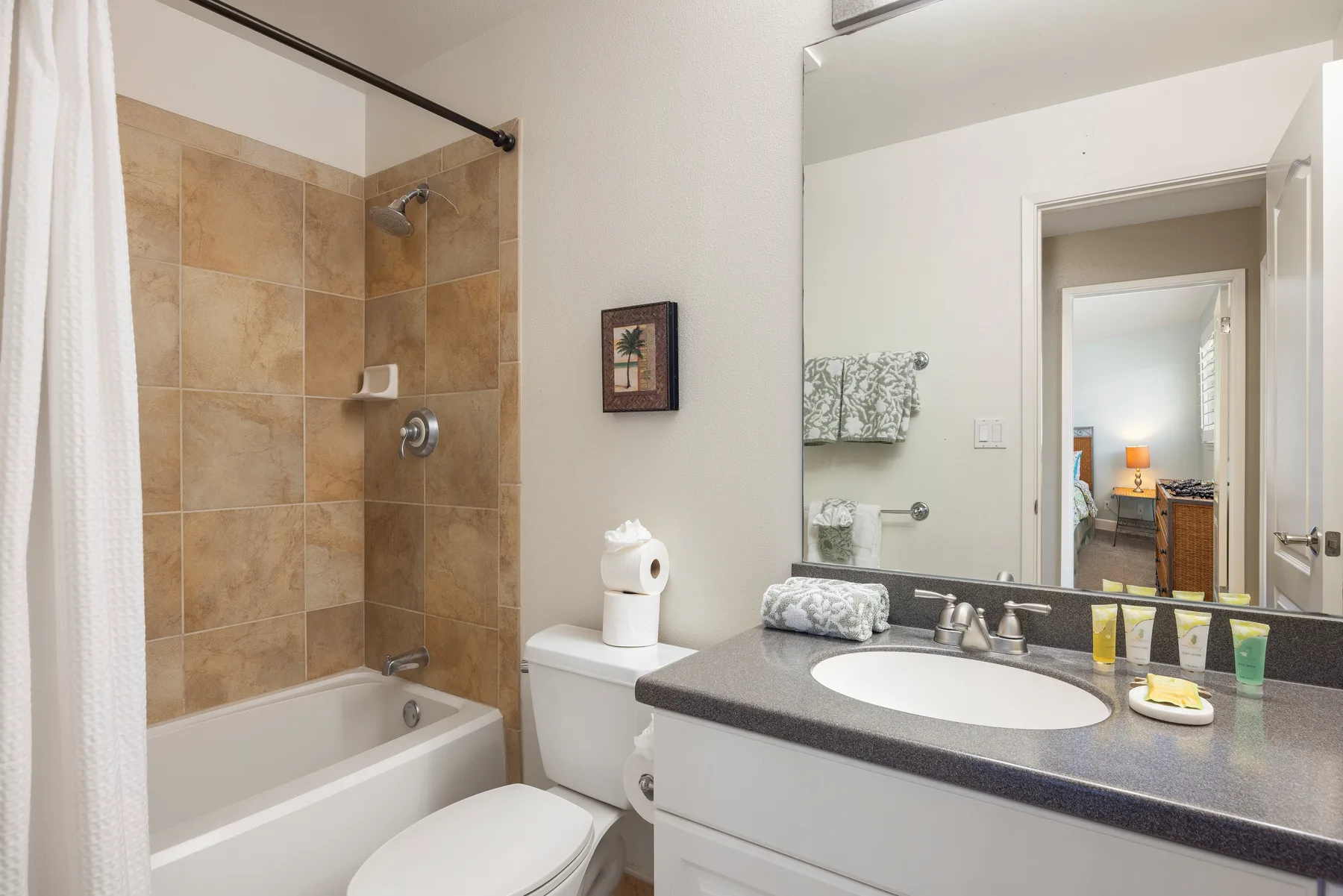 A bathroom with a bathtub, tiled shower wall, and sink vanity.