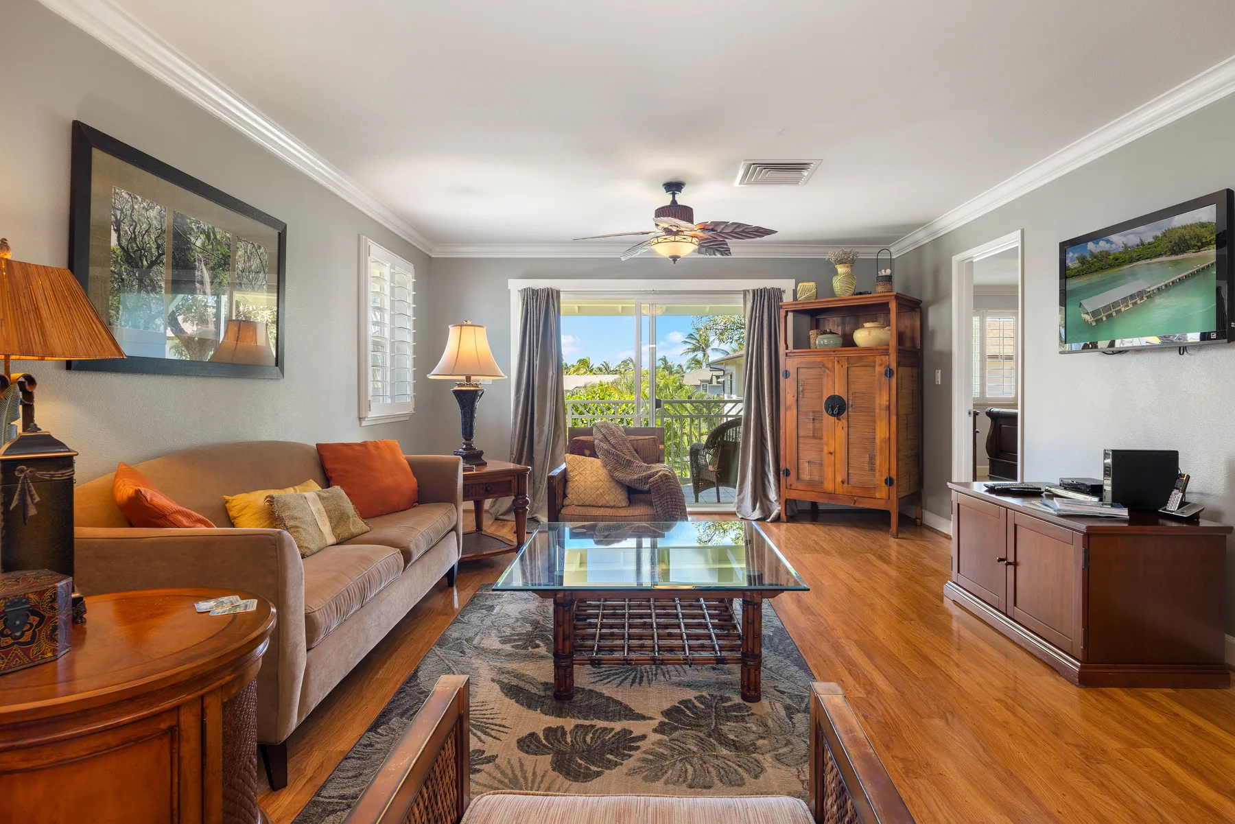 A living room with seating, a glass coffee table, and doors opening to a balcony.