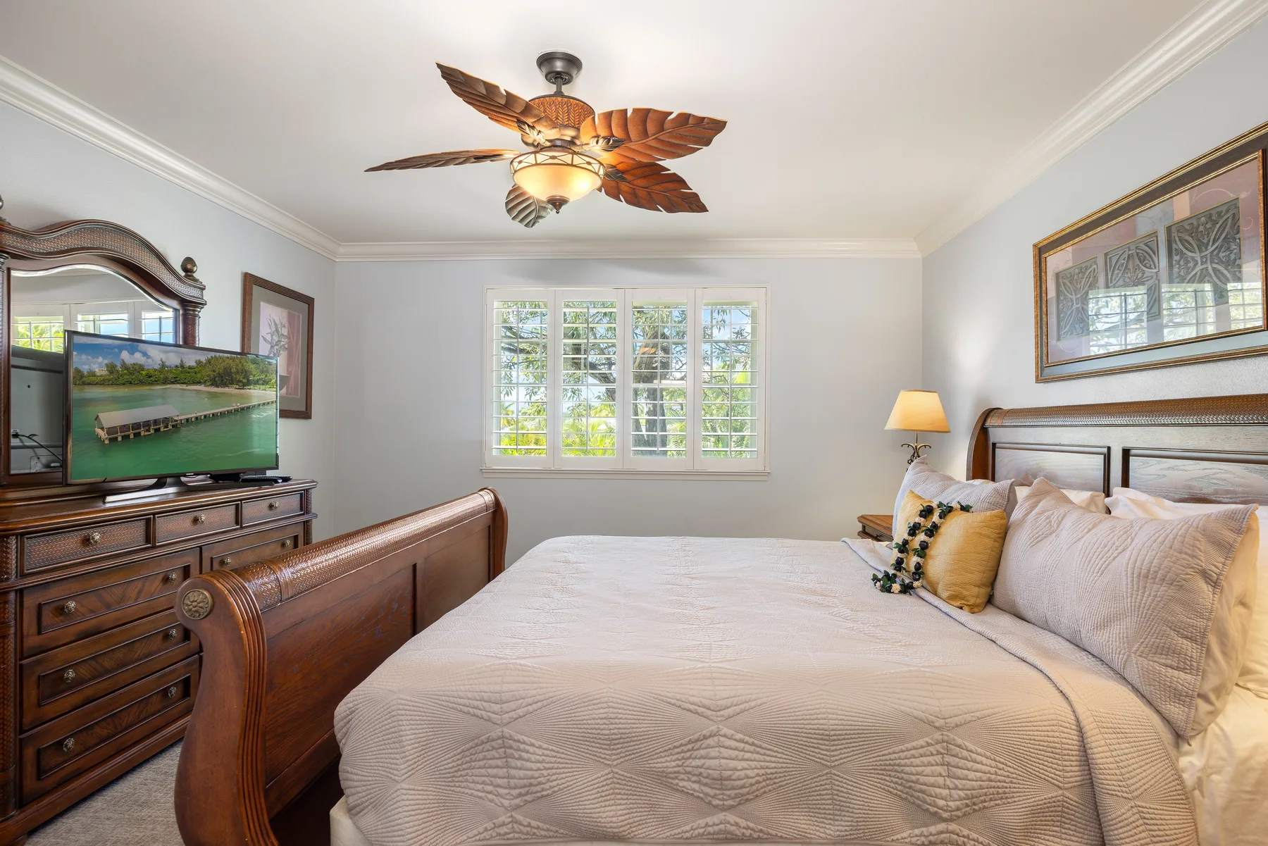 A bedroom with a large bed, a window, and a dresser with a television.