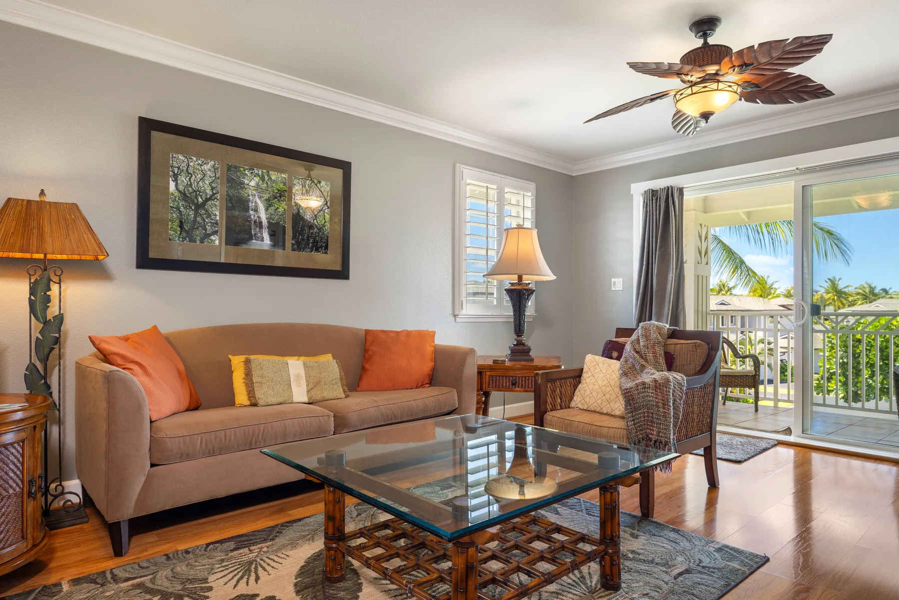 A living room with seating around a glass coffee table beside an open balcony.